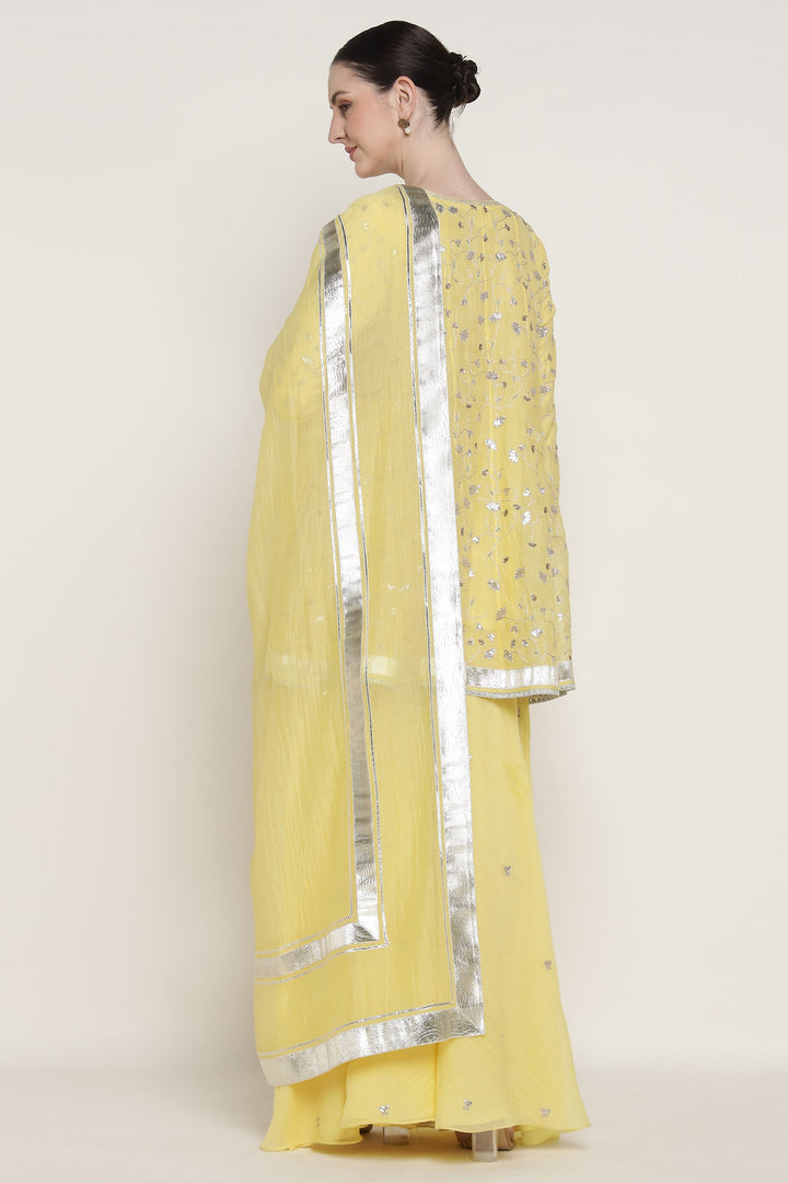 Woman wearing a yellow saree with silver border on a white background