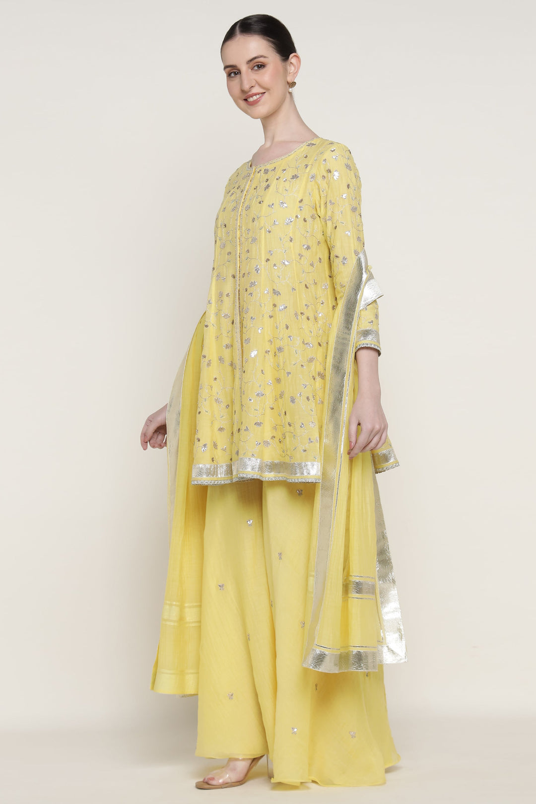 Woman wearing a yellow traditional outfit with a plain background