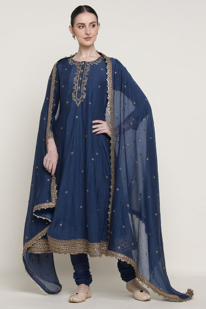 Woman wearing a blue traditional outfit with gold embroidery on a white background