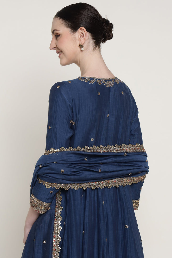 Woman wearing a blue traditional outfit with gold embroidery on a white background