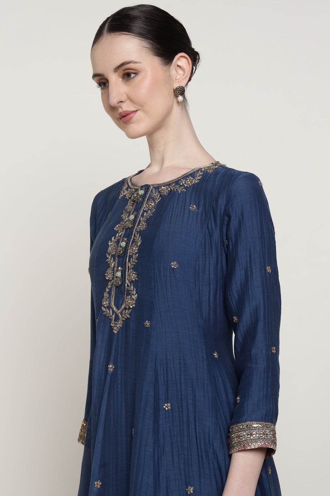 Woman wearing a blue embroidered dress against a white background