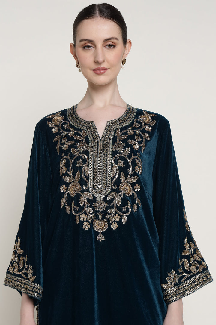 Woman wearing a dark blue velvet dress with gold embroidery on a white background