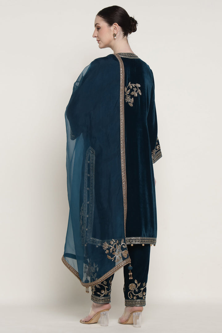 Woman wearing a dark blue embroidered outfit with a sheer dupatta on a white background