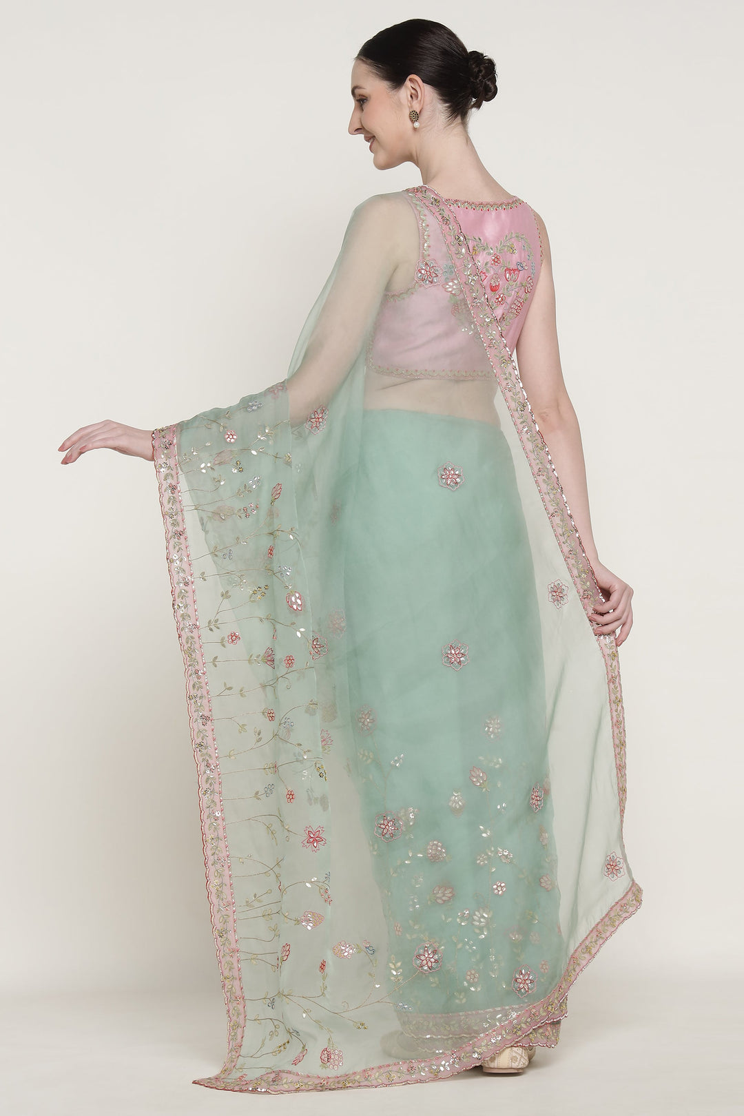 Woman wearing a light green saree with pink blouse on a white background