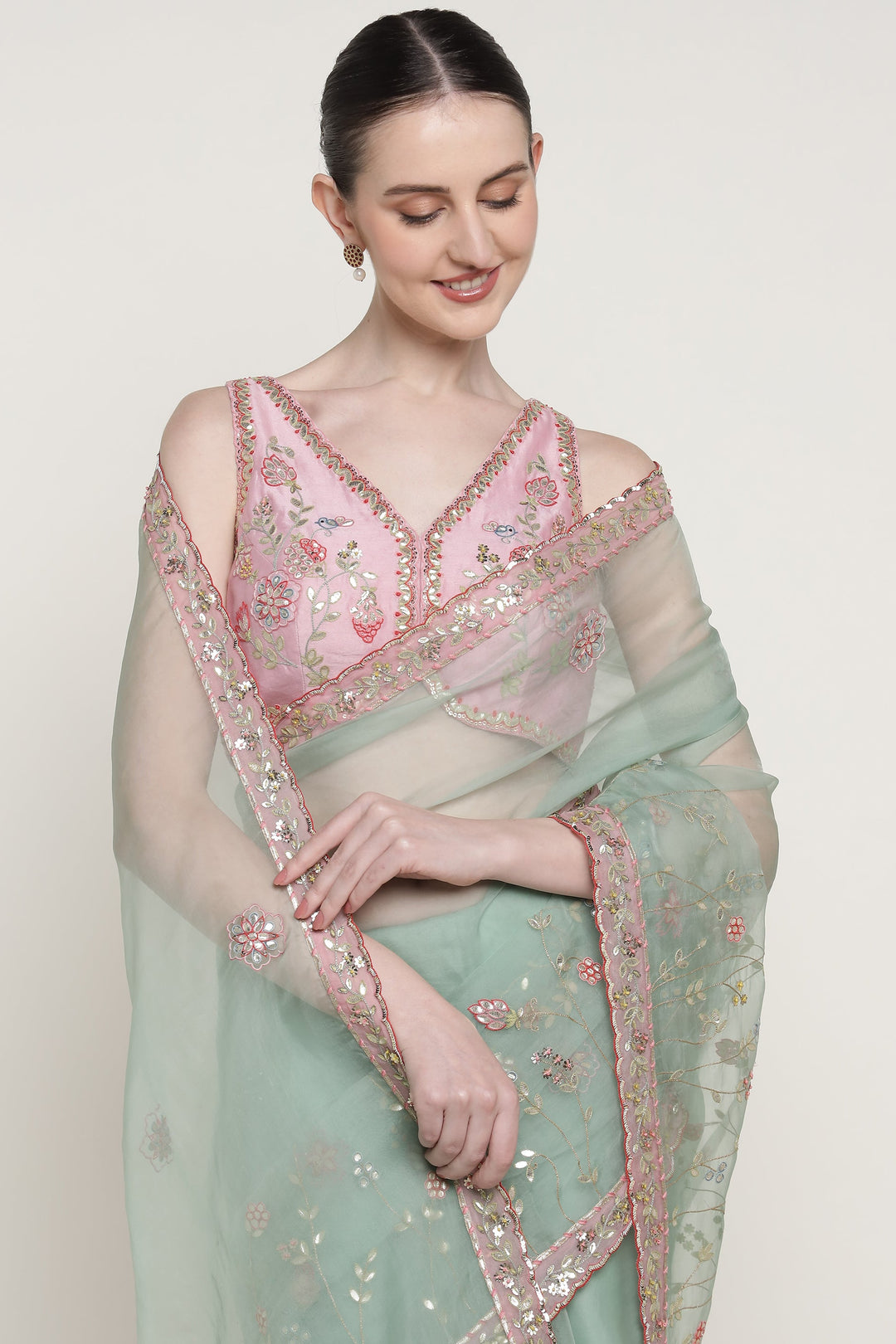 Woman wearing a light green saree with pink blouse against a white background