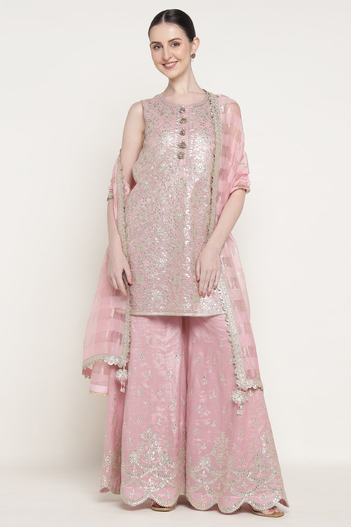 Woman wearing a pink embroidered traditional outfit with a white background