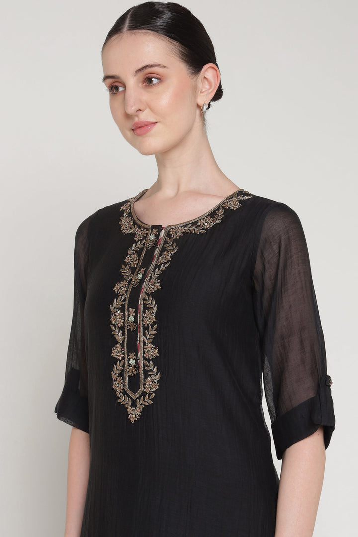 Black dress with gold embroidery on a plain background
