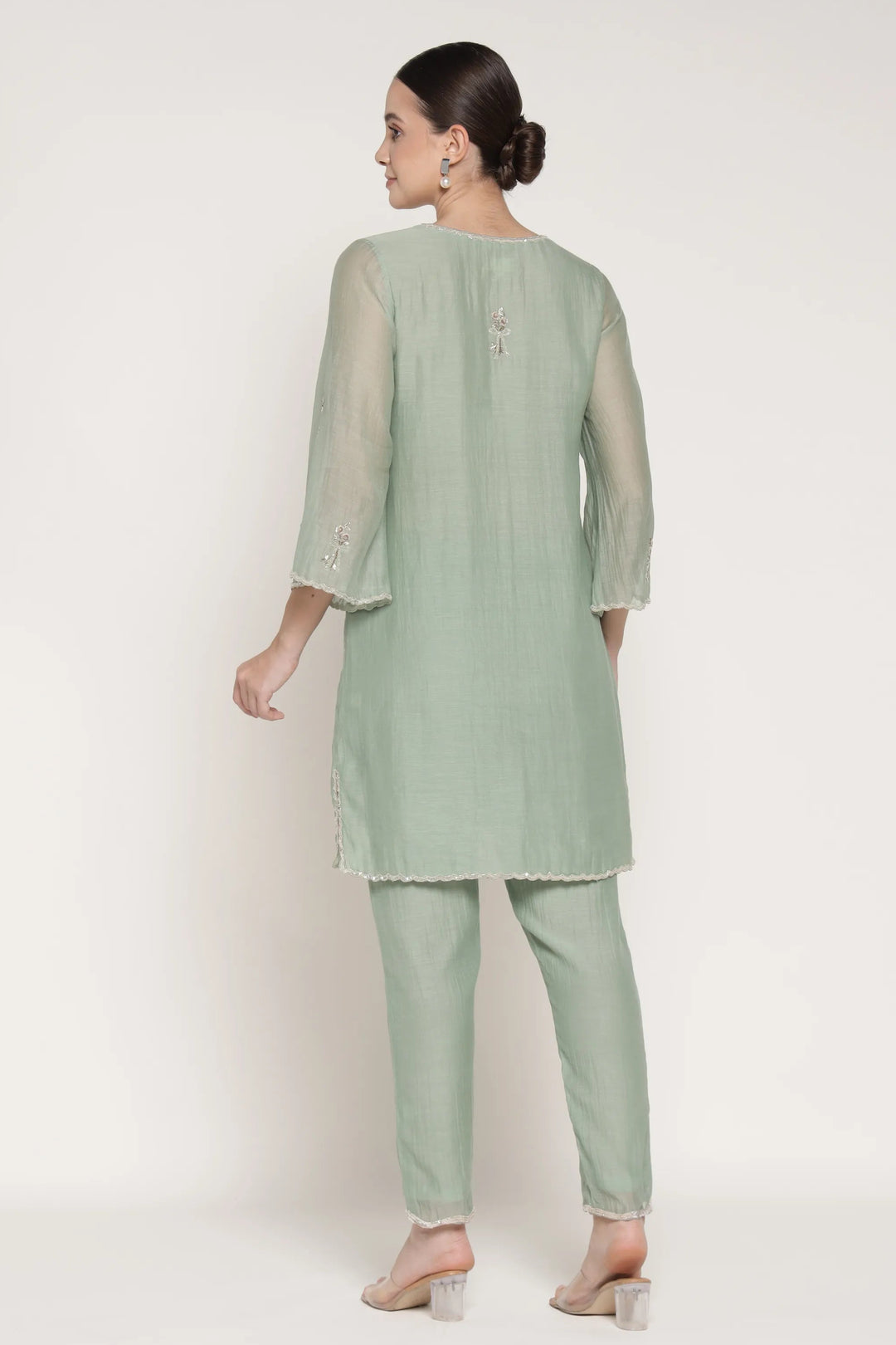 Woman wearing a light green kurta with pants on a white background