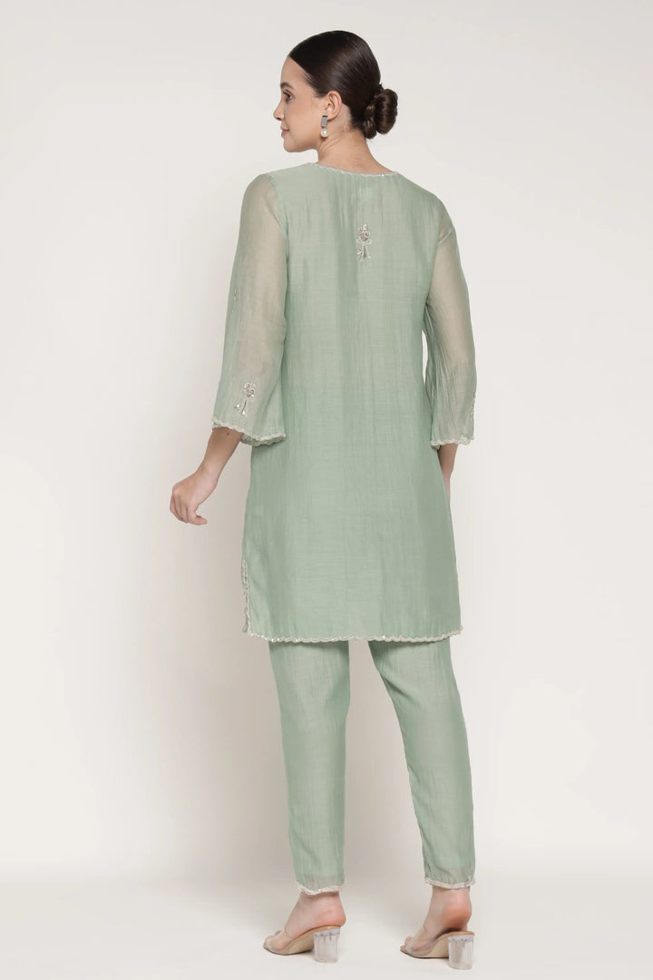 Woman wearing a light green kurta with pants on a white background