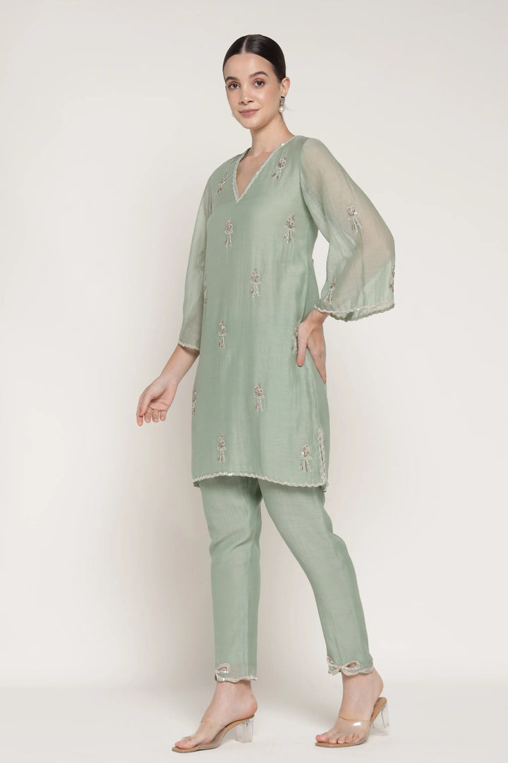 Woman wearing a light green outfit with a matching top and pants on a white background