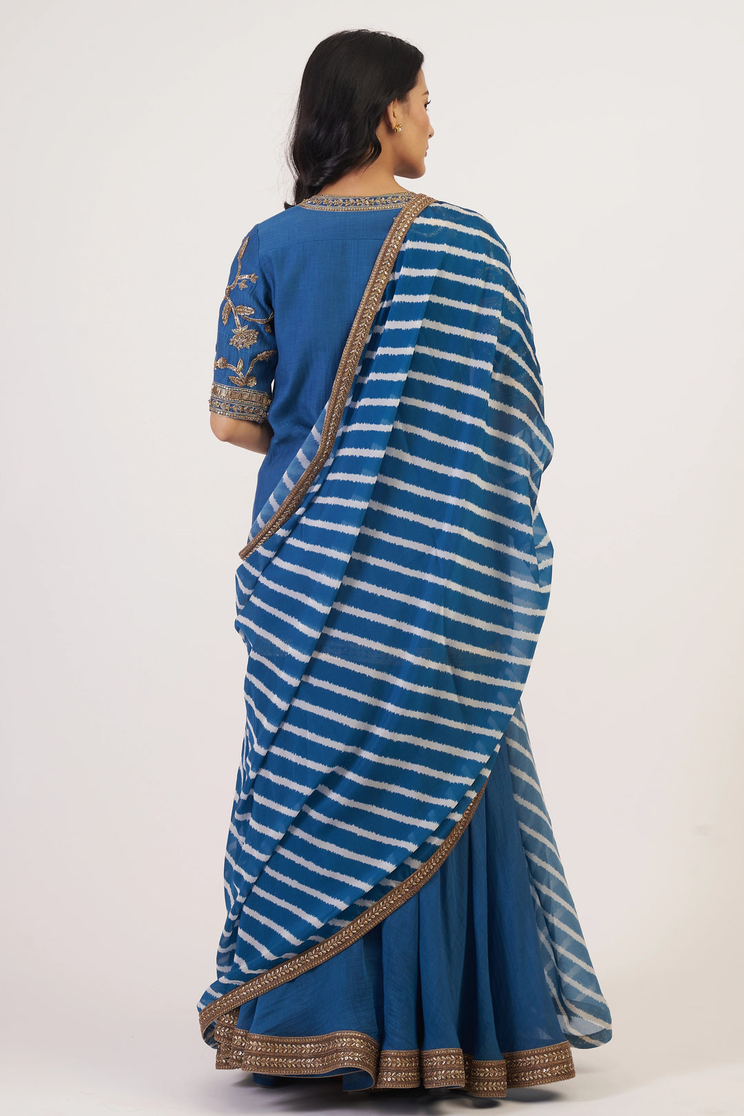 Woman wearing a blue and white striped saree with a plain background