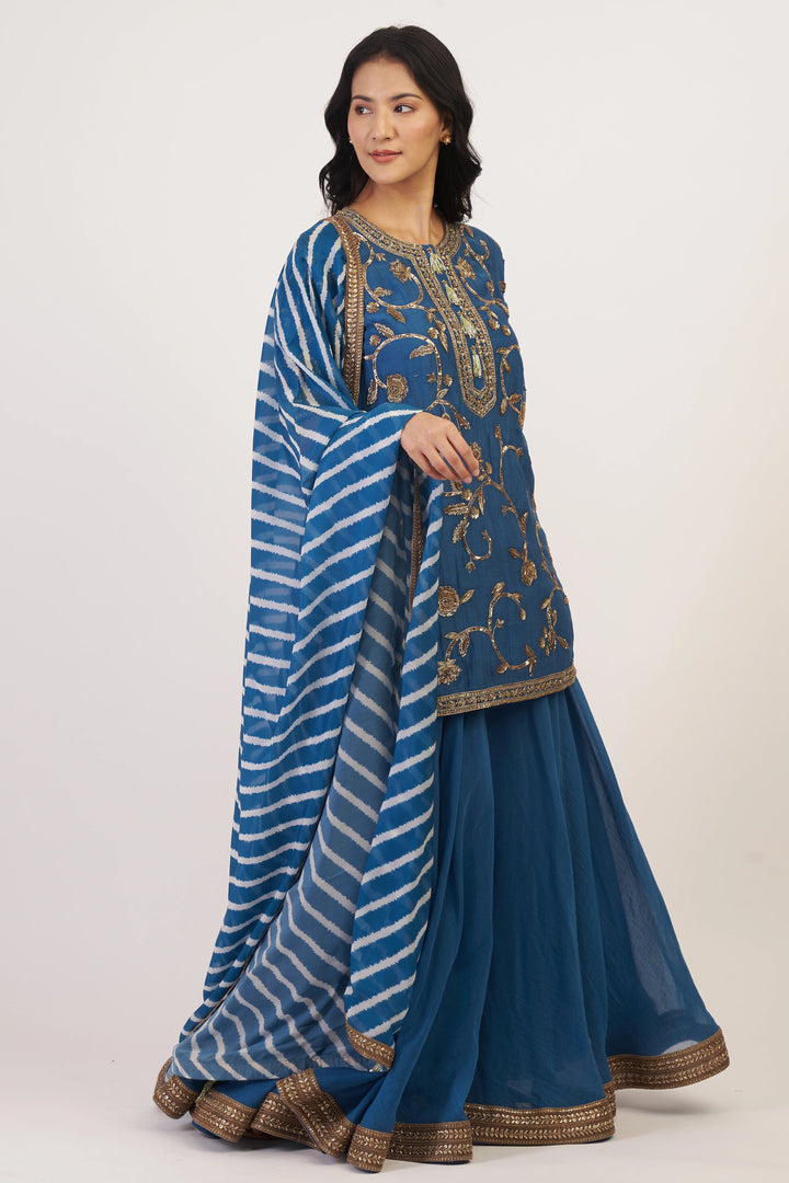 Woman wearing a blue embroidered traditional outfit with a white background