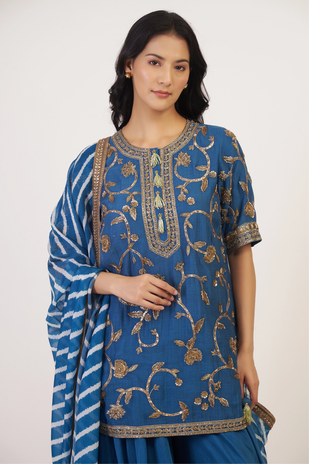 Woman wearing a blue embroidered traditional outfit on a white background