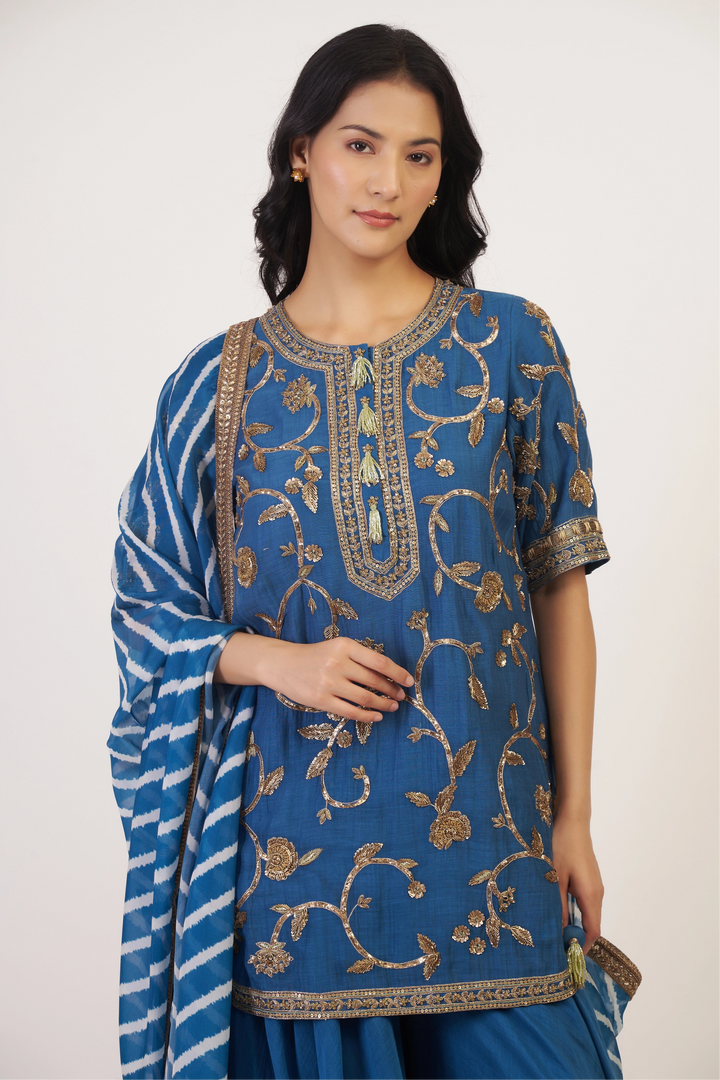 Woman wearing a blue embroidered traditional outfit on a white background