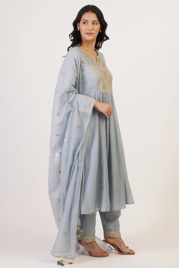 Woman wearing a light blue traditional outfit with a white background