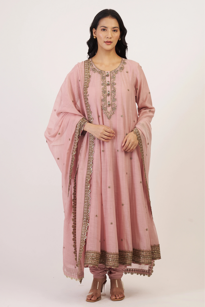 Woman wearing a pink traditional outfit with gold embroidery on a white background