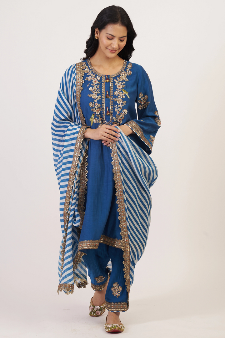 Woman wearing a blue embroidered traditional outfit with a white background