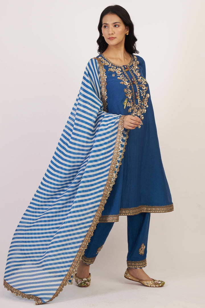 Woman wearing a blue traditional outfit with a striped dupatta on a white background