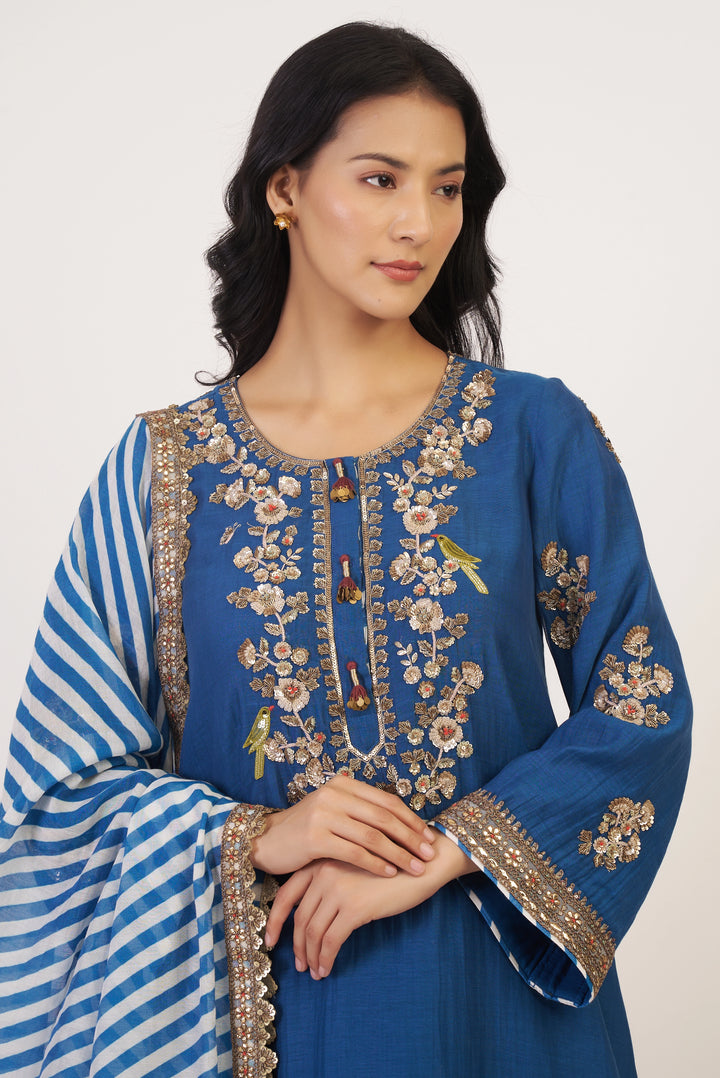 Woman wearing a blue embroidered traditional outfit with a white background