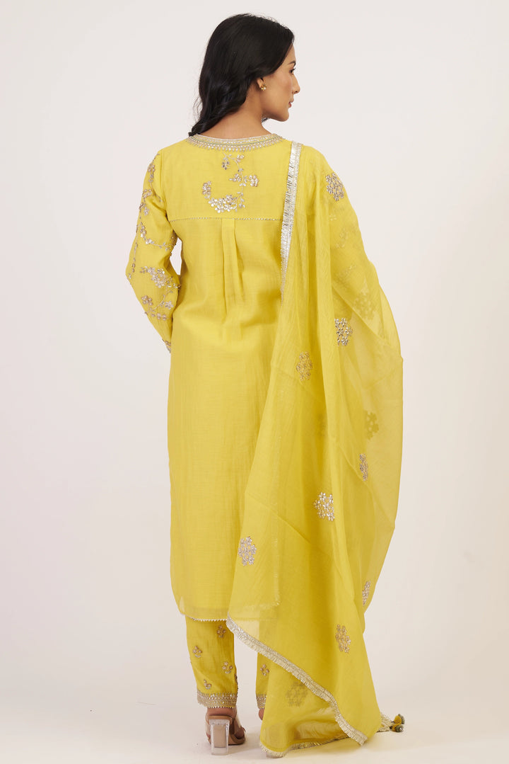 Woman wearing a yellow traditional outfit with embroidery on a white background
