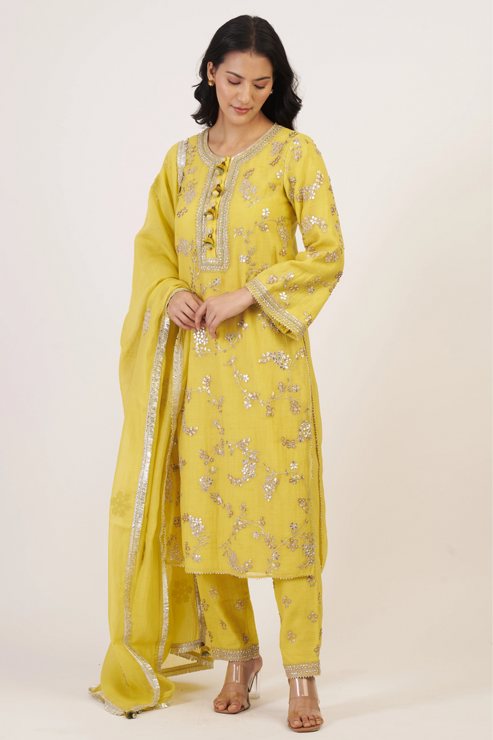 Woman wearing a yellow embroidered traditional outfit on a white background