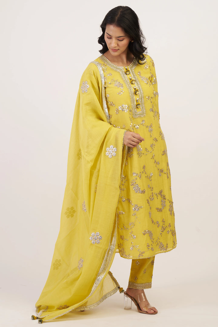 Woman wearing a yellow embroidered outfit with a dupatta on a white background
