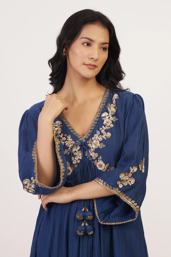 Woman wearing a blue dress with floral embroidery on a white background