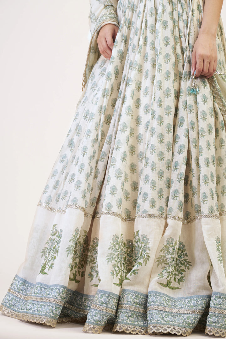 White traditional outfit with green floral patterns on a plain background