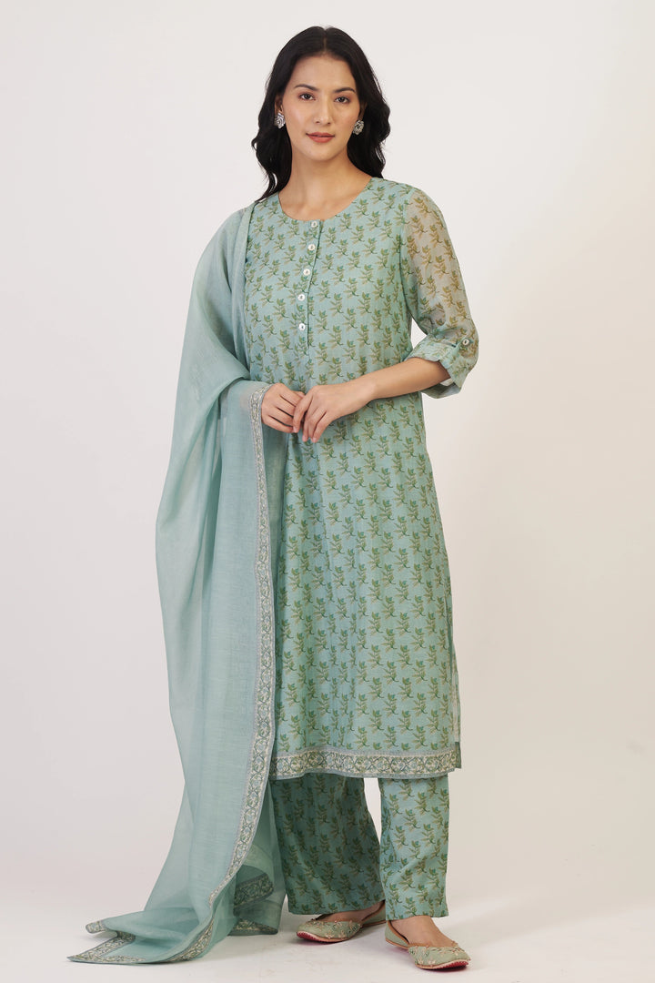 Woman wearing a green traditional outfit with a matching dupatta on a white background