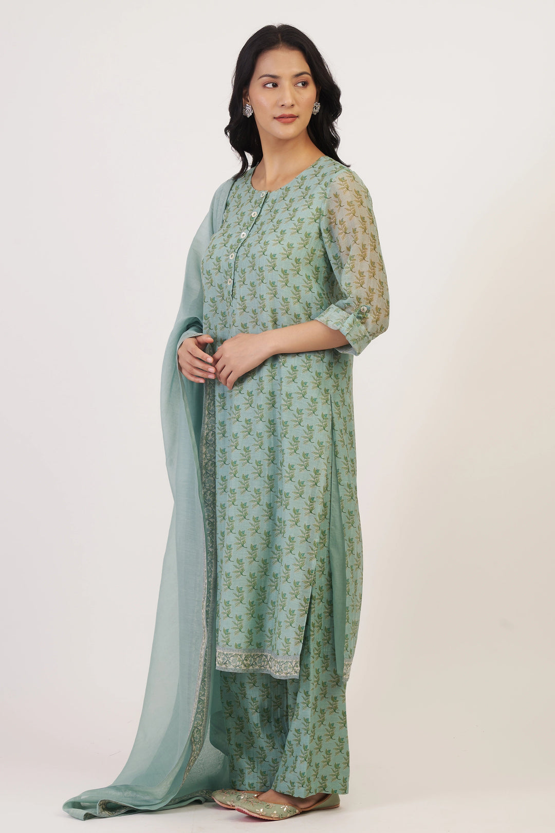 Woman wearing a green traditional outfit with a matching dupatta on a white background