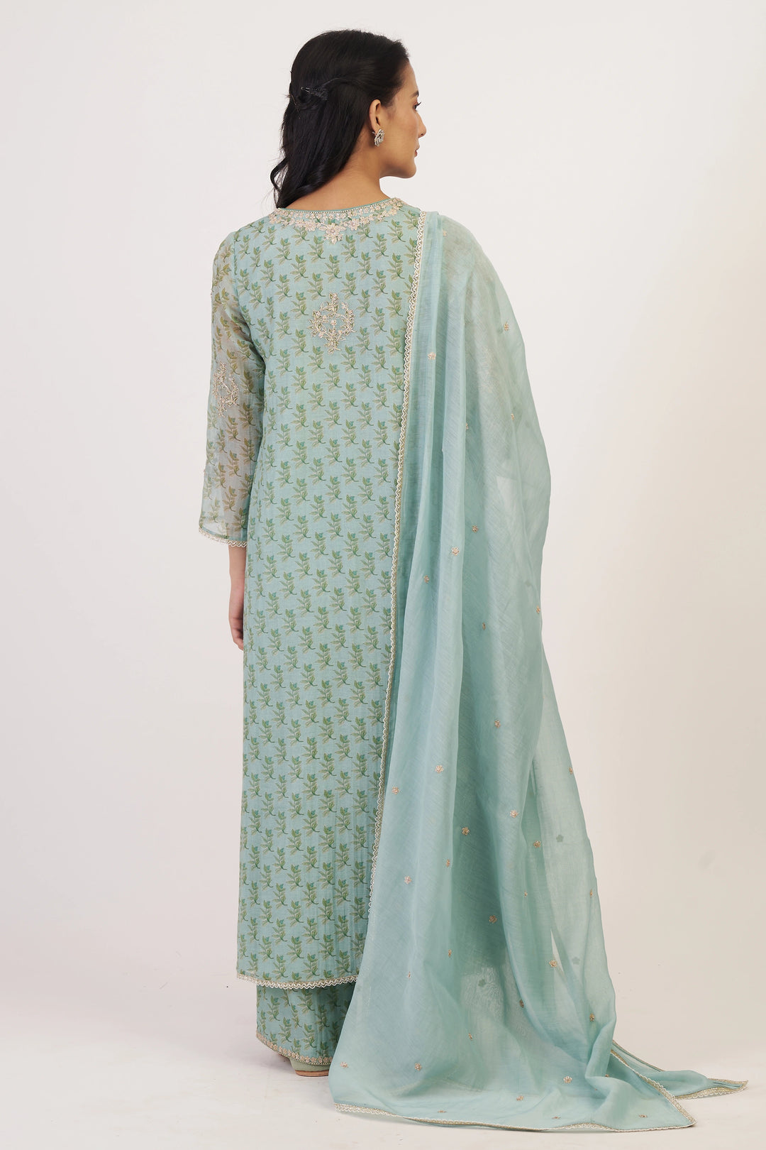 Woman wearing a light green traditional outfit with a matching dupatta on a white background