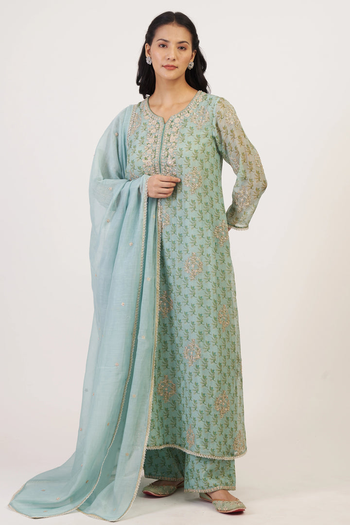 Woman wearing a light blue and green traditional outfit with a matching dupatta on a white background