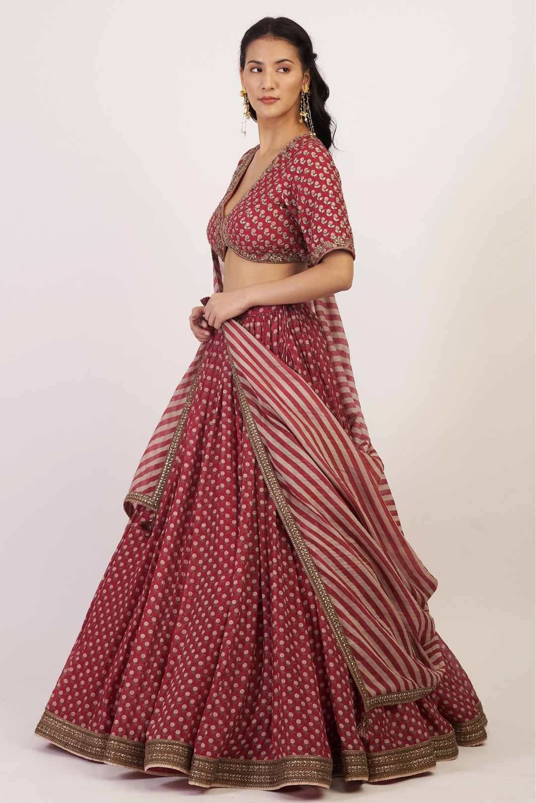 Woman wearing a maroon and gold traditional outfit on a white background