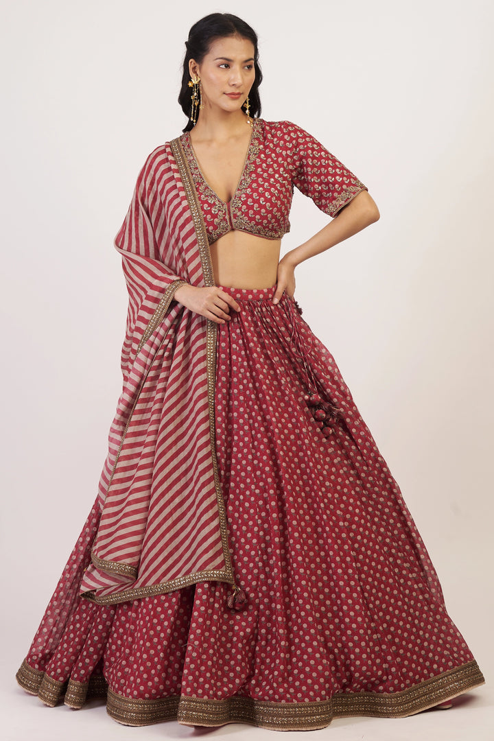 Woman wearing a traditional maroon and white patterned outfit on a plain background