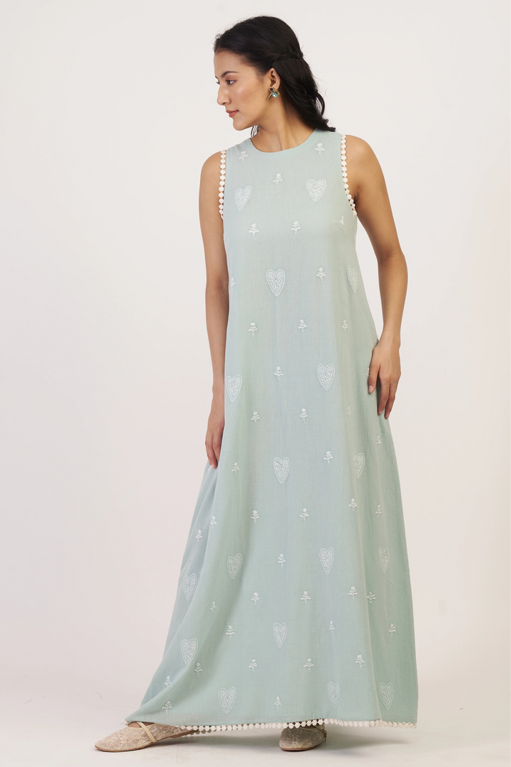 Woman wearing a light blue dress with white patterns on a plain background