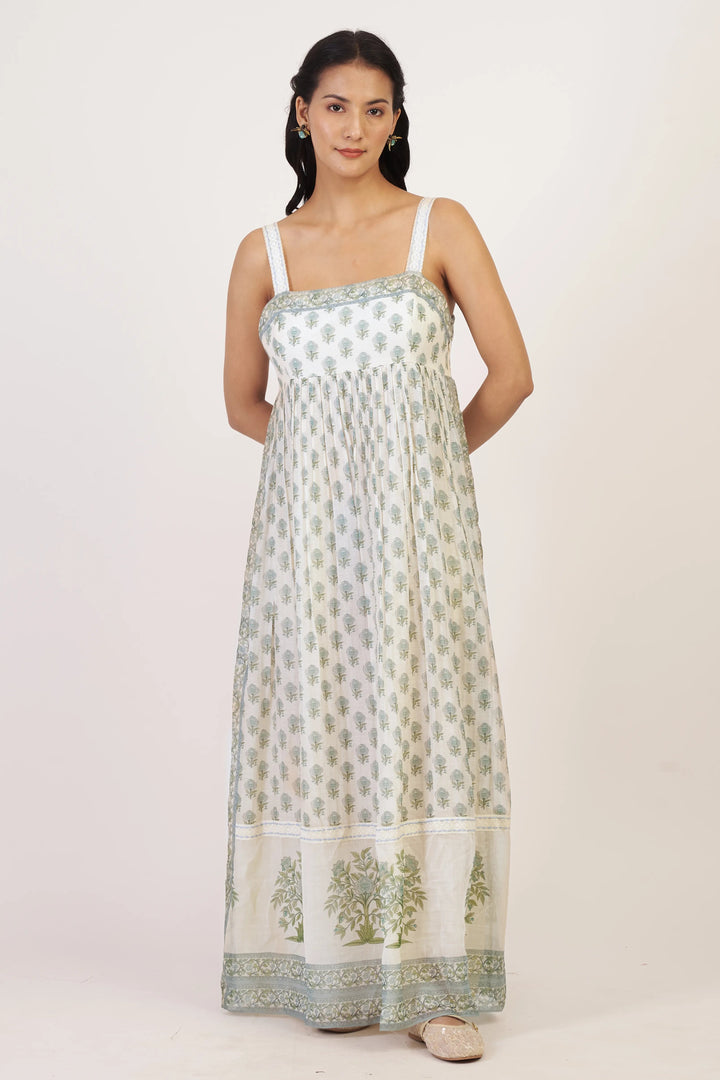 Woman wearing a long, light-colored dress with floral patterns on a white background