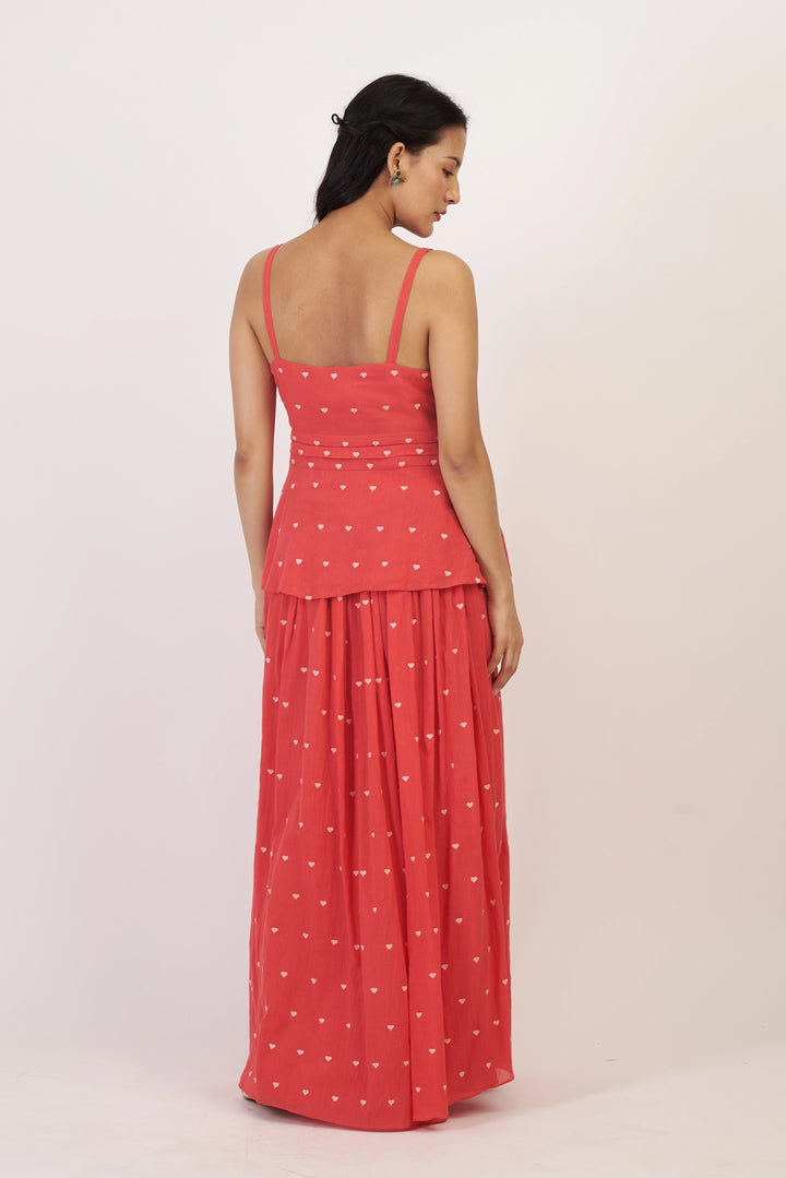 Woman wearing a coral dress with white patterns on a light pink background