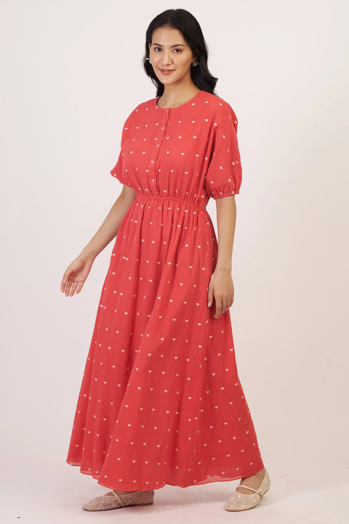 Woman wearing a red dress with white patterns on a plain background