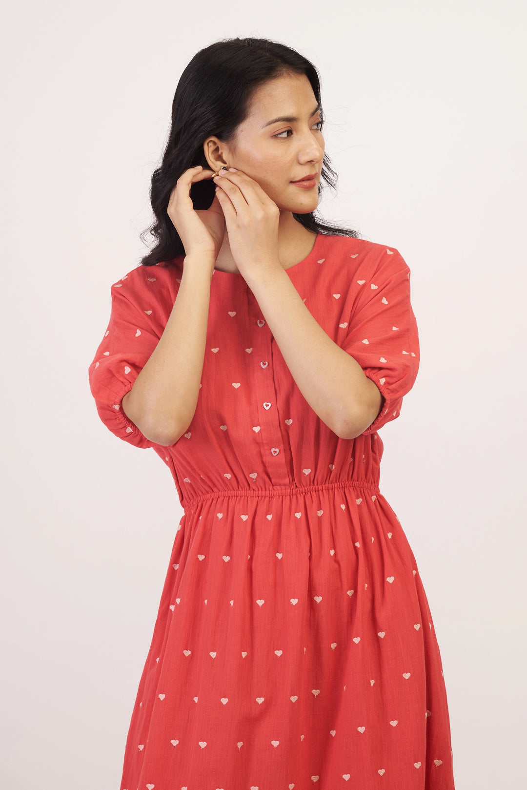 Woman wearing a red dress with heart patterns against a white background
