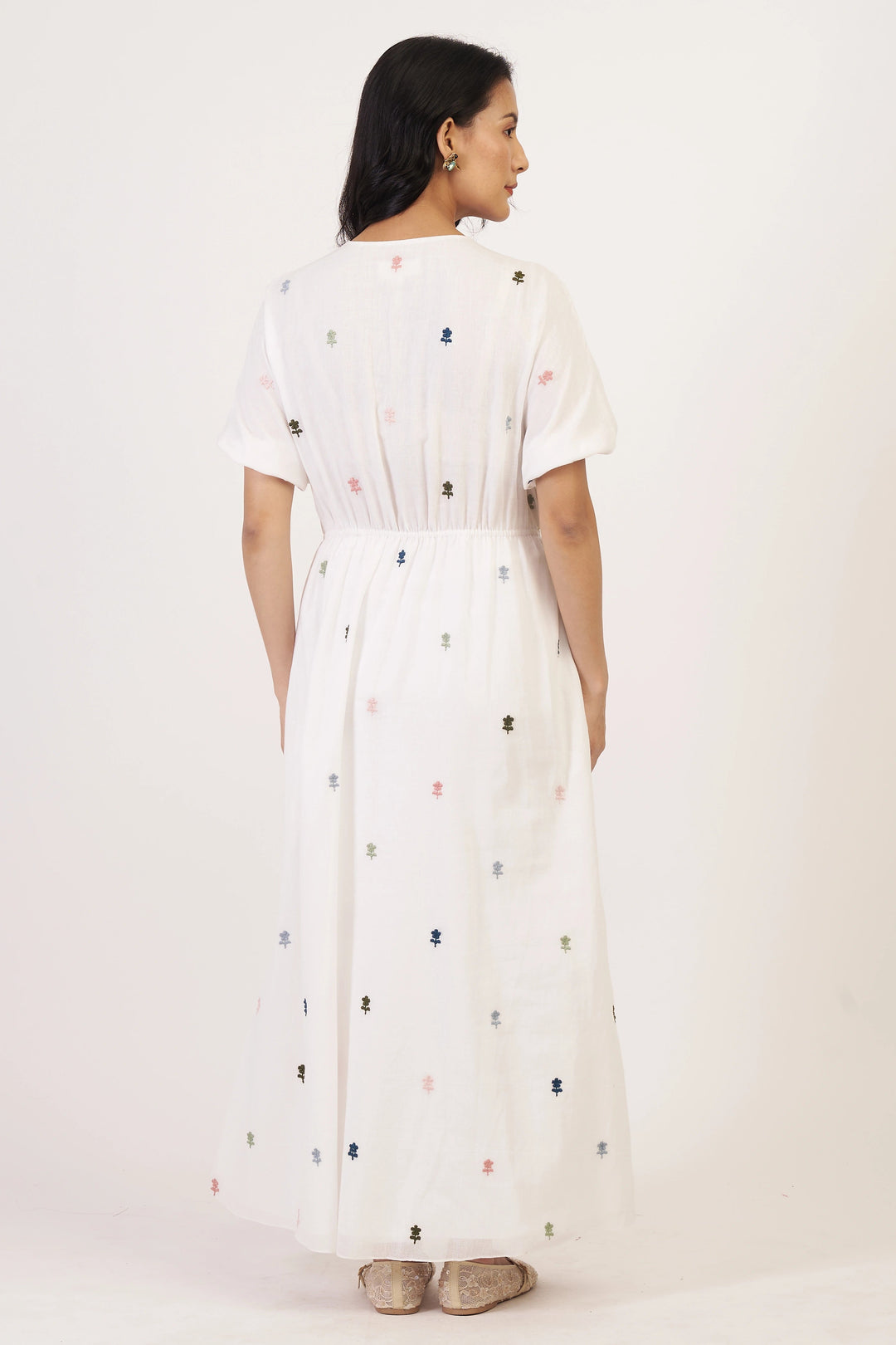 Woman wearing a white dress with colorful patterns on a white background