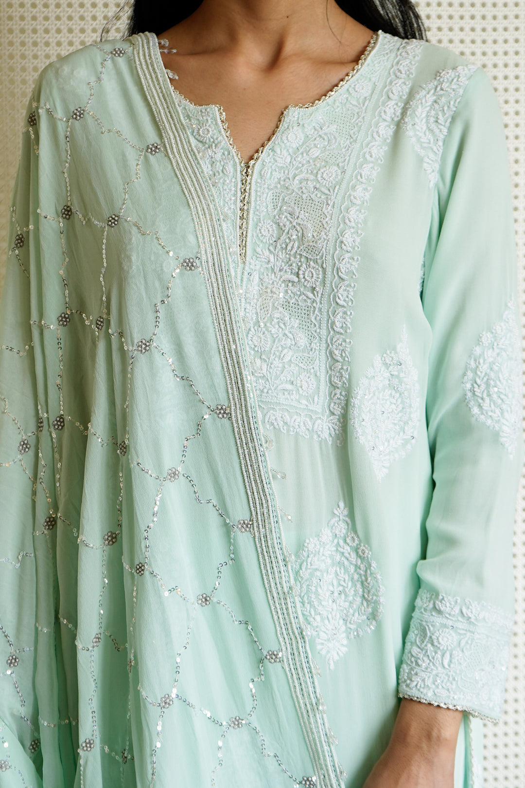 Light green embroidered dress with intricate patterns on a neutral background