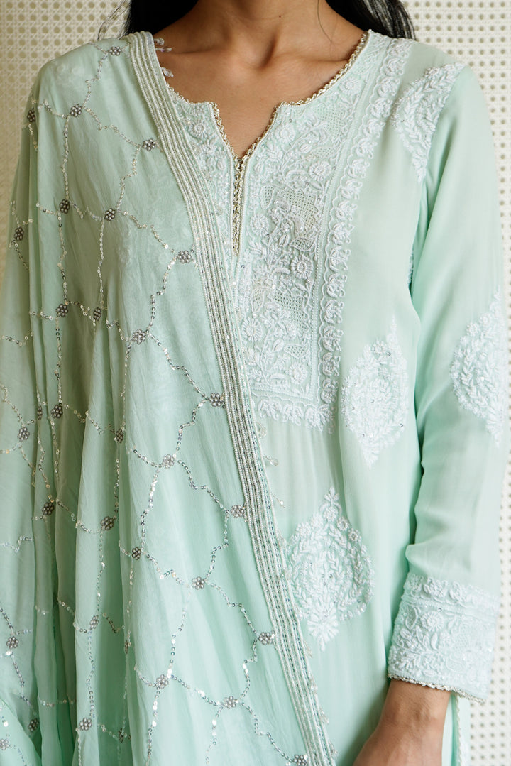 Light green embroidered dress with intricate patterns on a neutral background